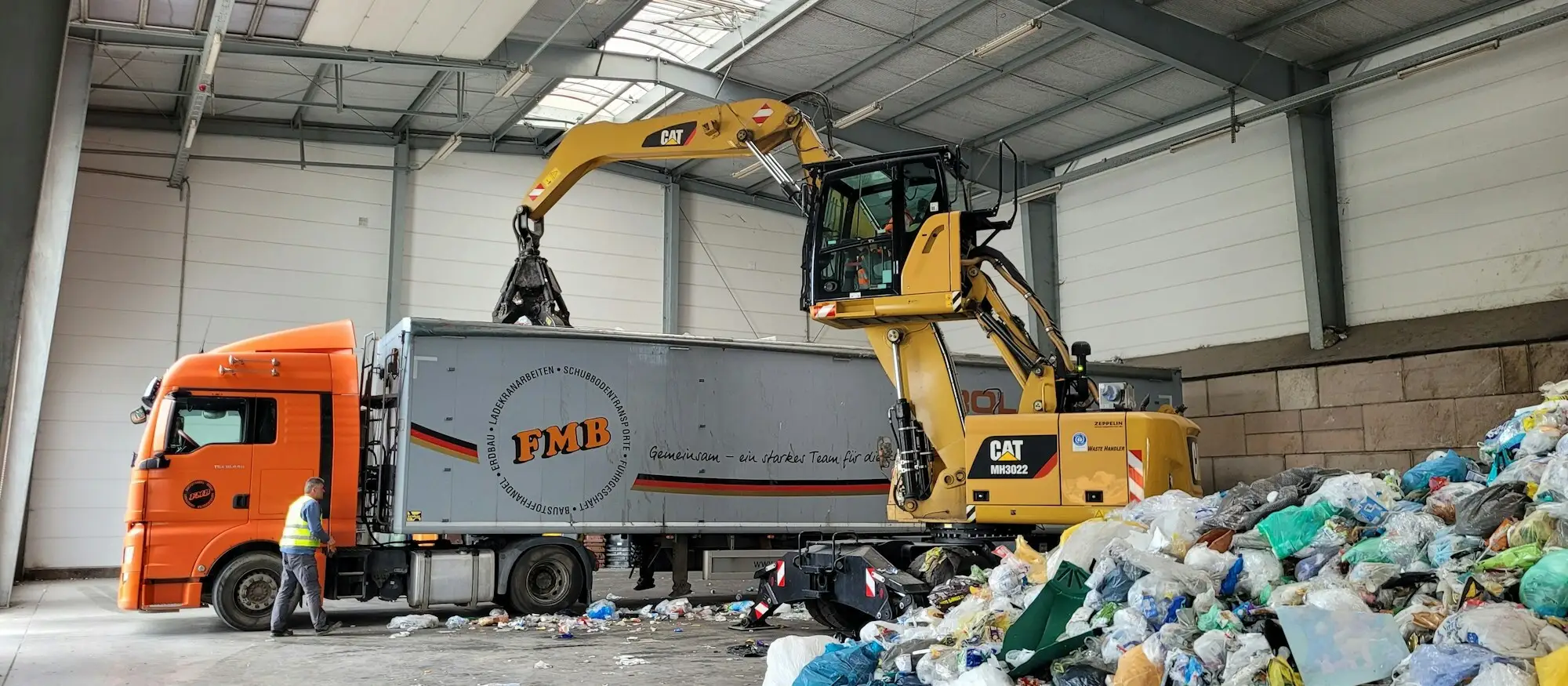 A wheeled loader and articulated lorry inside a UK waste transfer station